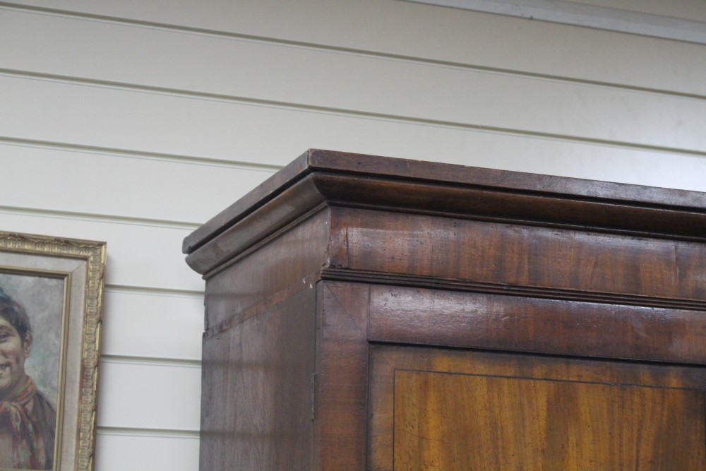 A Regency mahogany linen press with two doors enclosing five slides, two short drawers and two graduated long drawers, on swept bracket